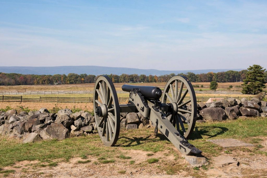 A canon used during battle sitting along a rock border in a battlefield