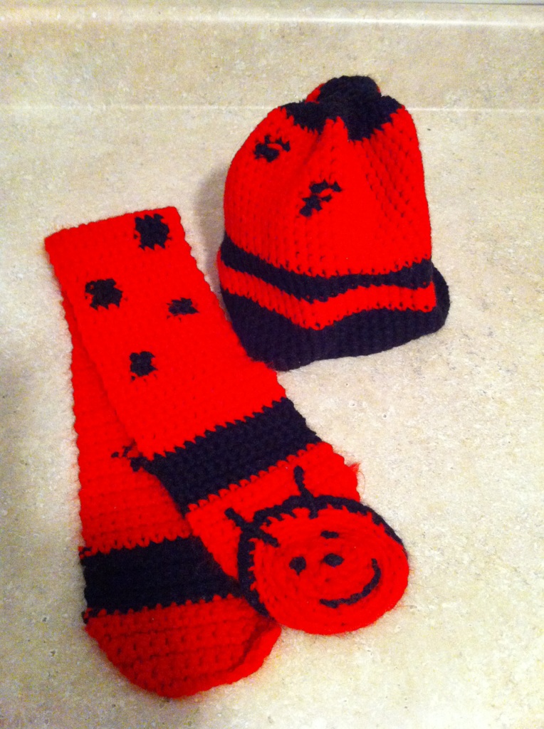 red with black spots and stripes and a ladybug face crocheted child's scarf and hat set
