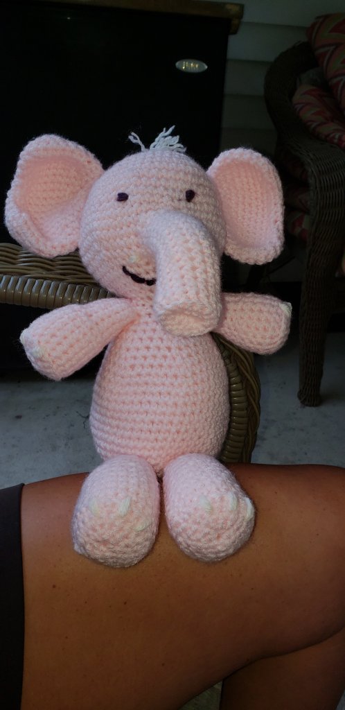 pink crocheted elephant doll with yarn sewn on for eyes, mouth, and hair
