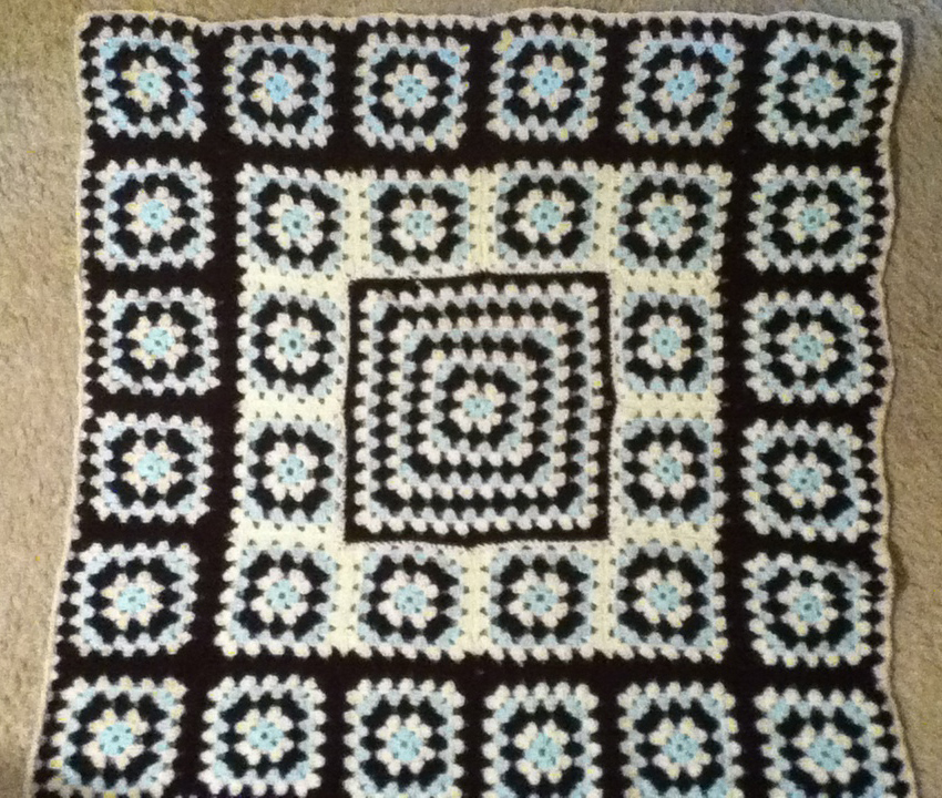 Crocheted Granny square baby blanket with brown, ivory, and light blue colors